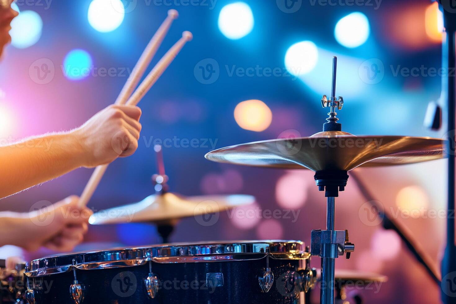 Close-up of drummer's hands playing drums on stage with bright lights. photo