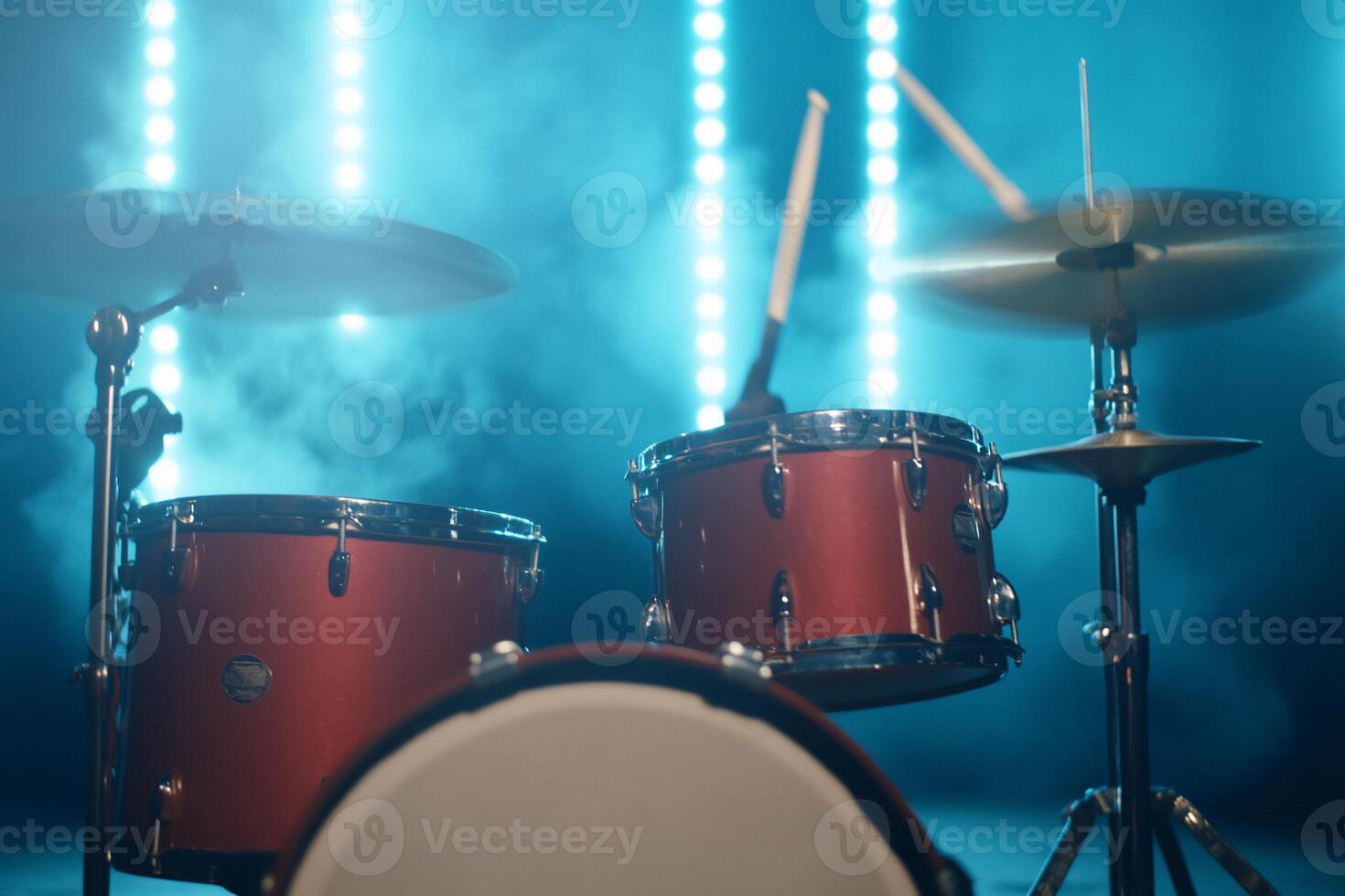 Red drum kit on stage with blue lights and smoke. photo