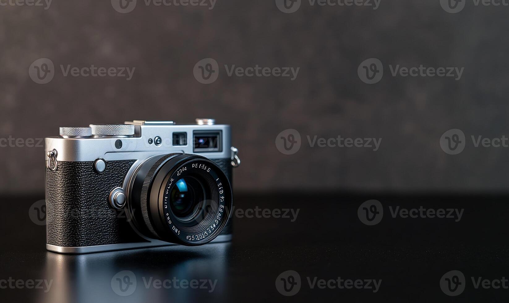 Silver rangefinder camera on dark surface. photo