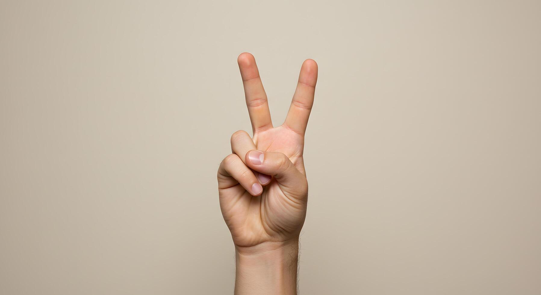 A Close-Up Shot of a Hand Showing the Victory Sign Against a Neutral Background photo