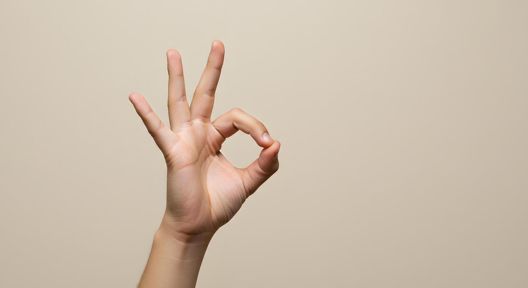 Hand Gesturing Okay Symbol Against Beige Background A Simple Studio Shot of a Hand Forming the Okay Sign photo