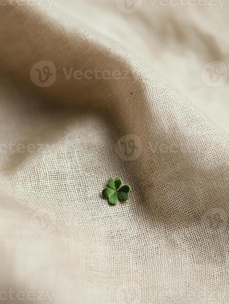 Natural linen fabric background with delicate texture and green clover accent photo
