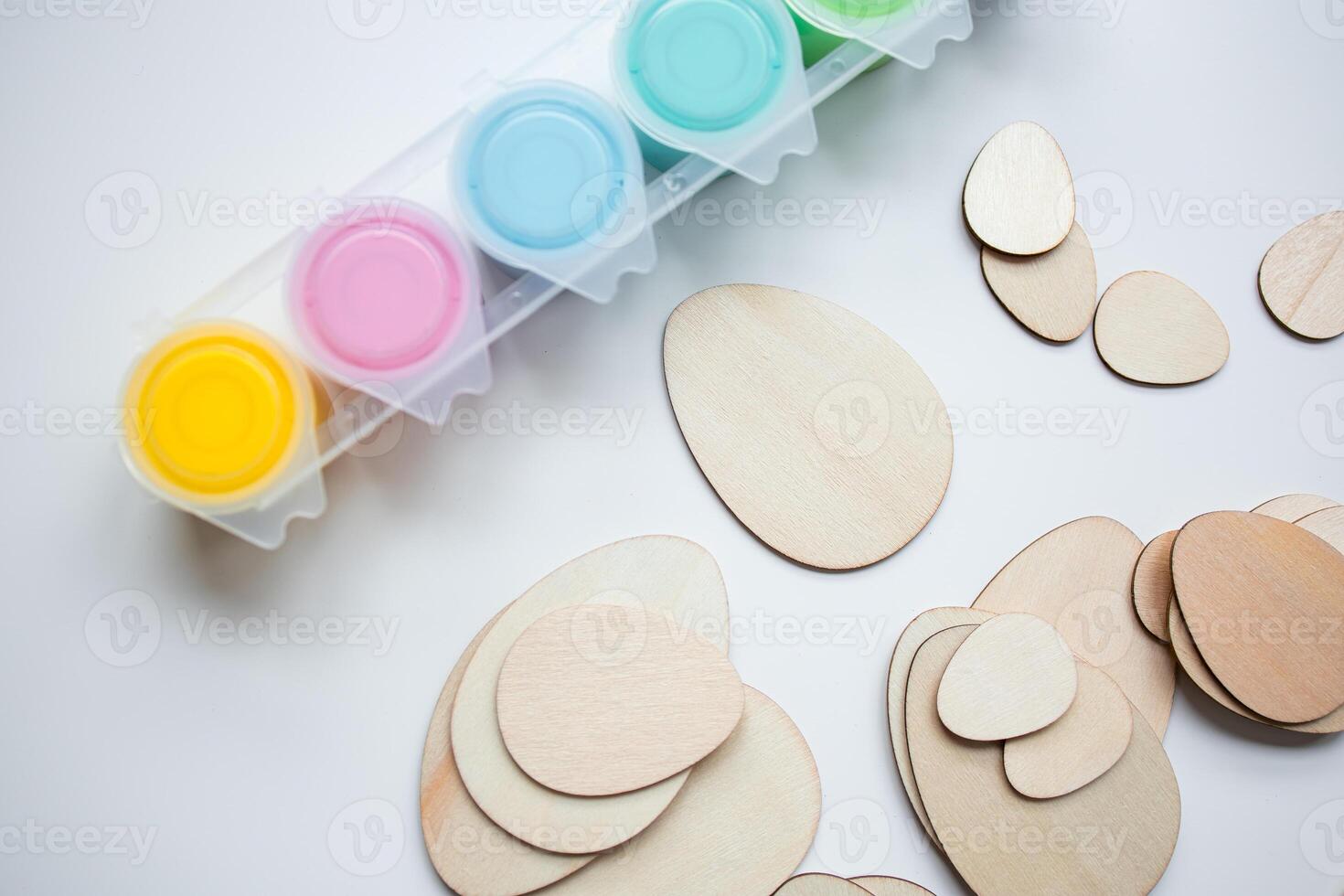 Colorful paints and wooden Easter egg shapes for crafting and creativity photo
