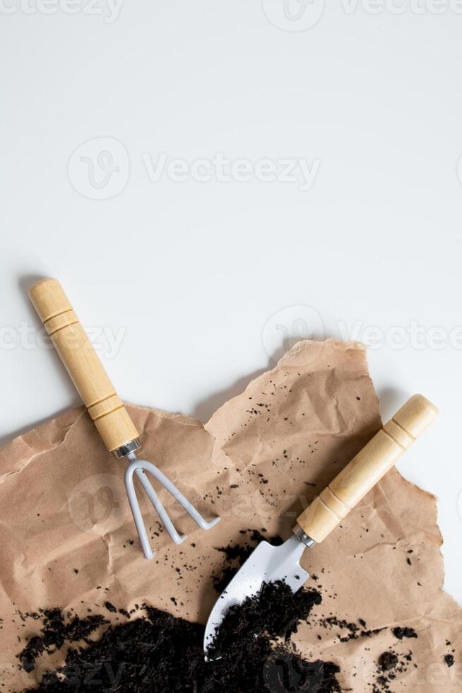 Gardening tools with wooden handles on brown paper and soil background photo