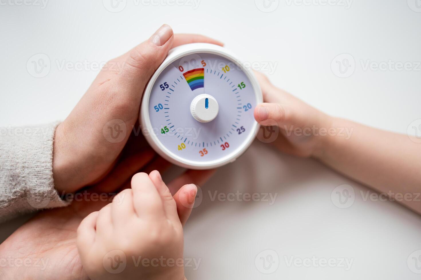 Adult and child hands holding colorful timer on white background photo