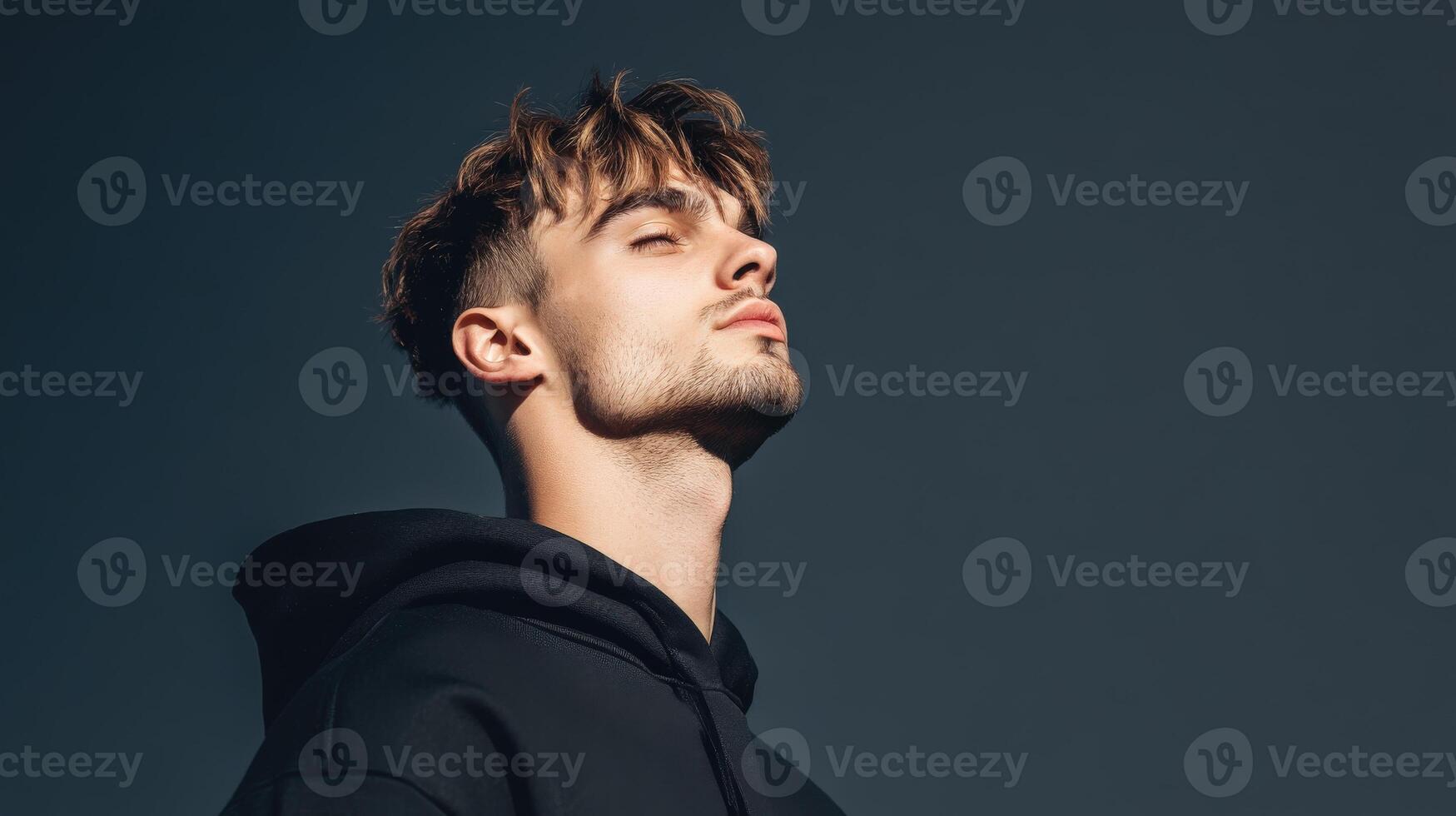 Young Man in Black Hoodie Contemplating Outdoors photo