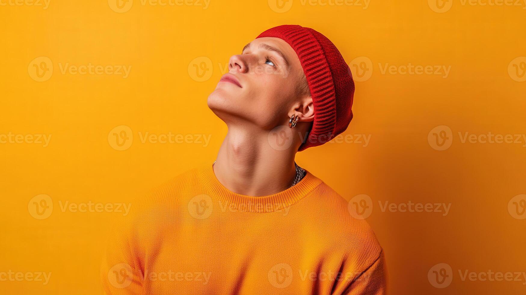 Young Man in Red Beanie Gazes Upward Against Yellow Background photo