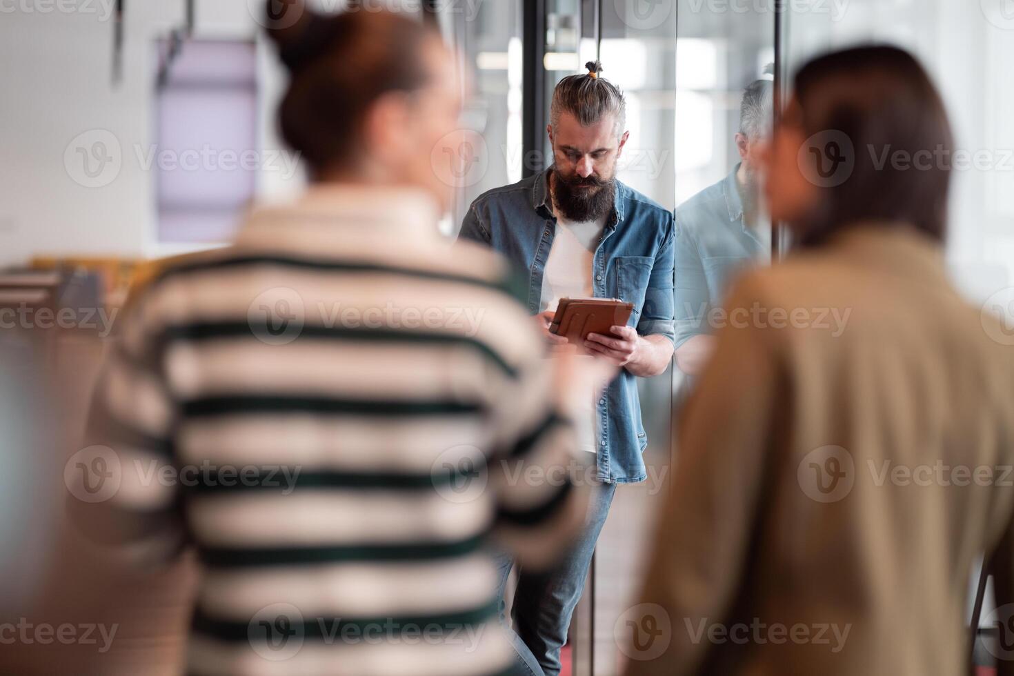 Senior bearded businessman, IT professional, trader, and crypto investor using a digital tablet in a modern coworking space. Tech-savvy professional working in an open office startup environment photo