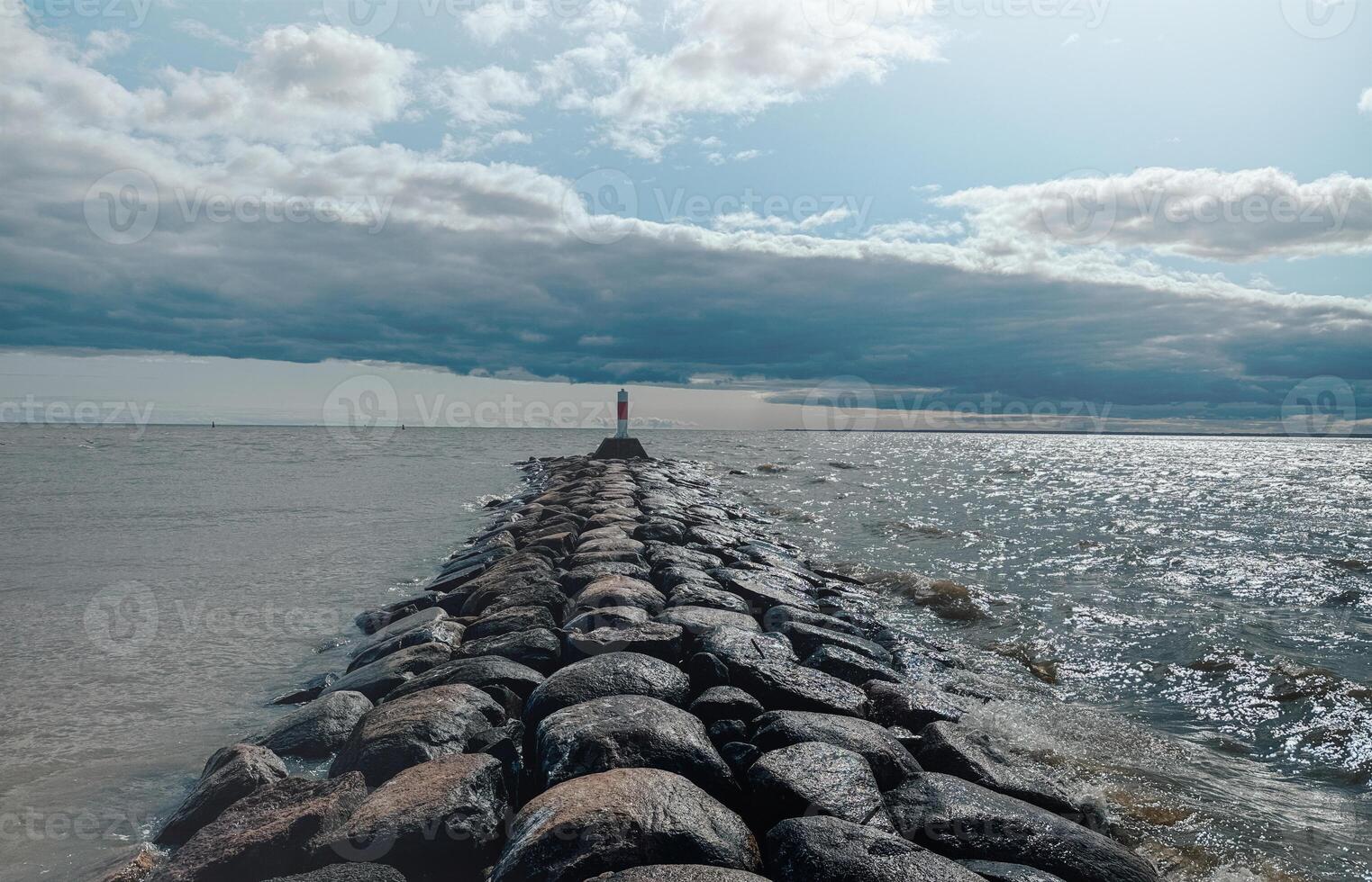 A lighthouse stands on a rock in front of the sea photo