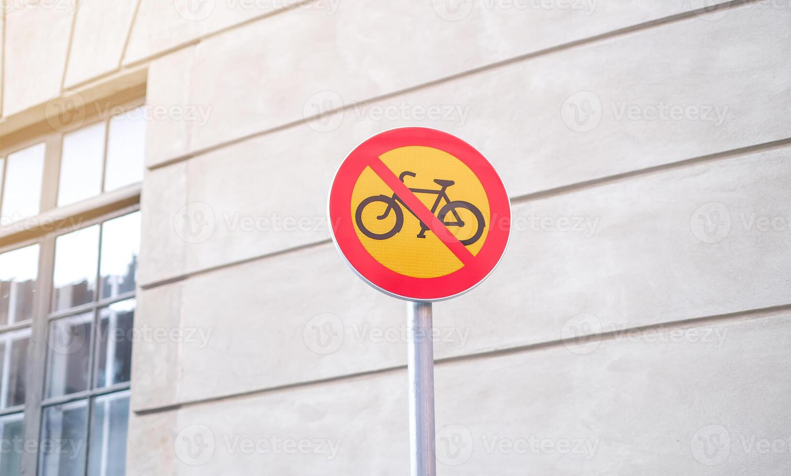 A no bike sign is on a pole in front of a building photo