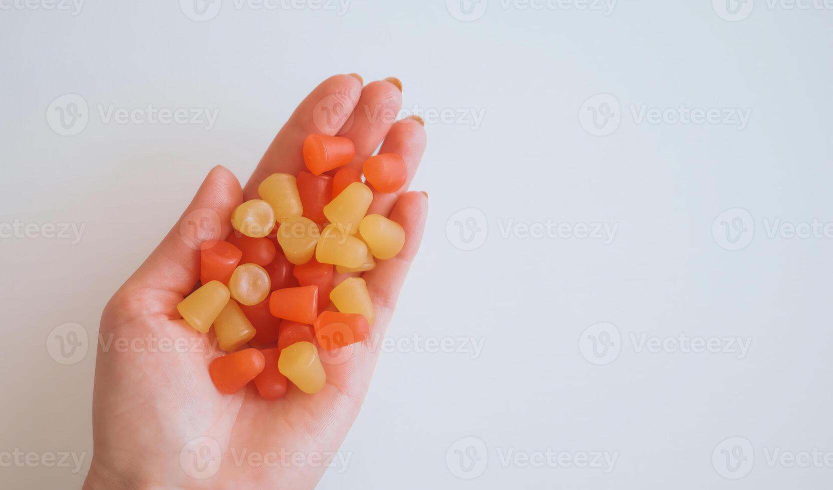 A hand holding a bunch of multivitamin gummies in a variety of colors photo