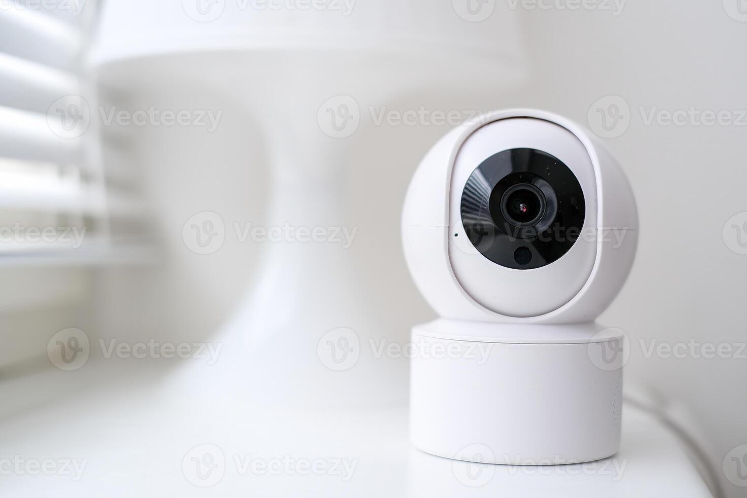 Smart home security camera on a white table near a window. photo