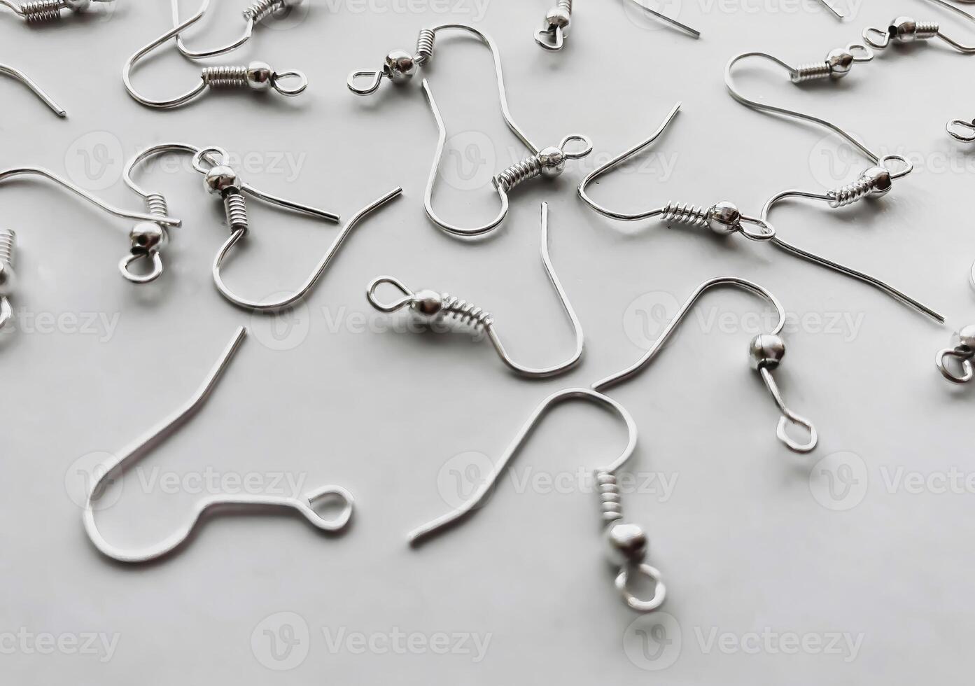 Close-up of silver earring hooks scattered on a white background. photo