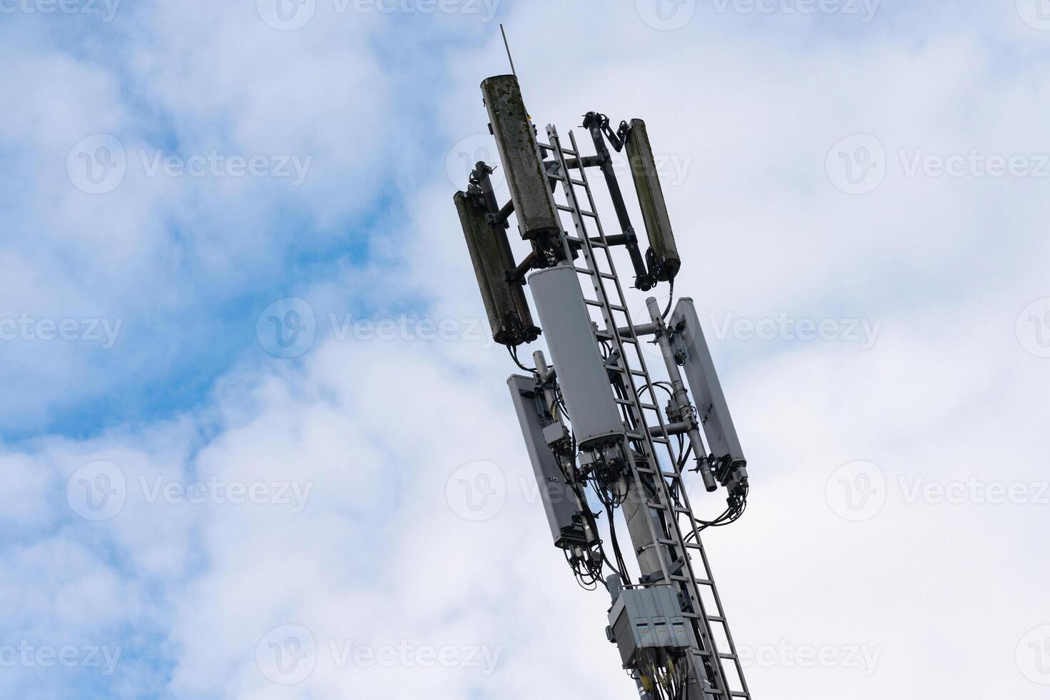 Cell tower stands tall against a cloudy sky in urban setting photo