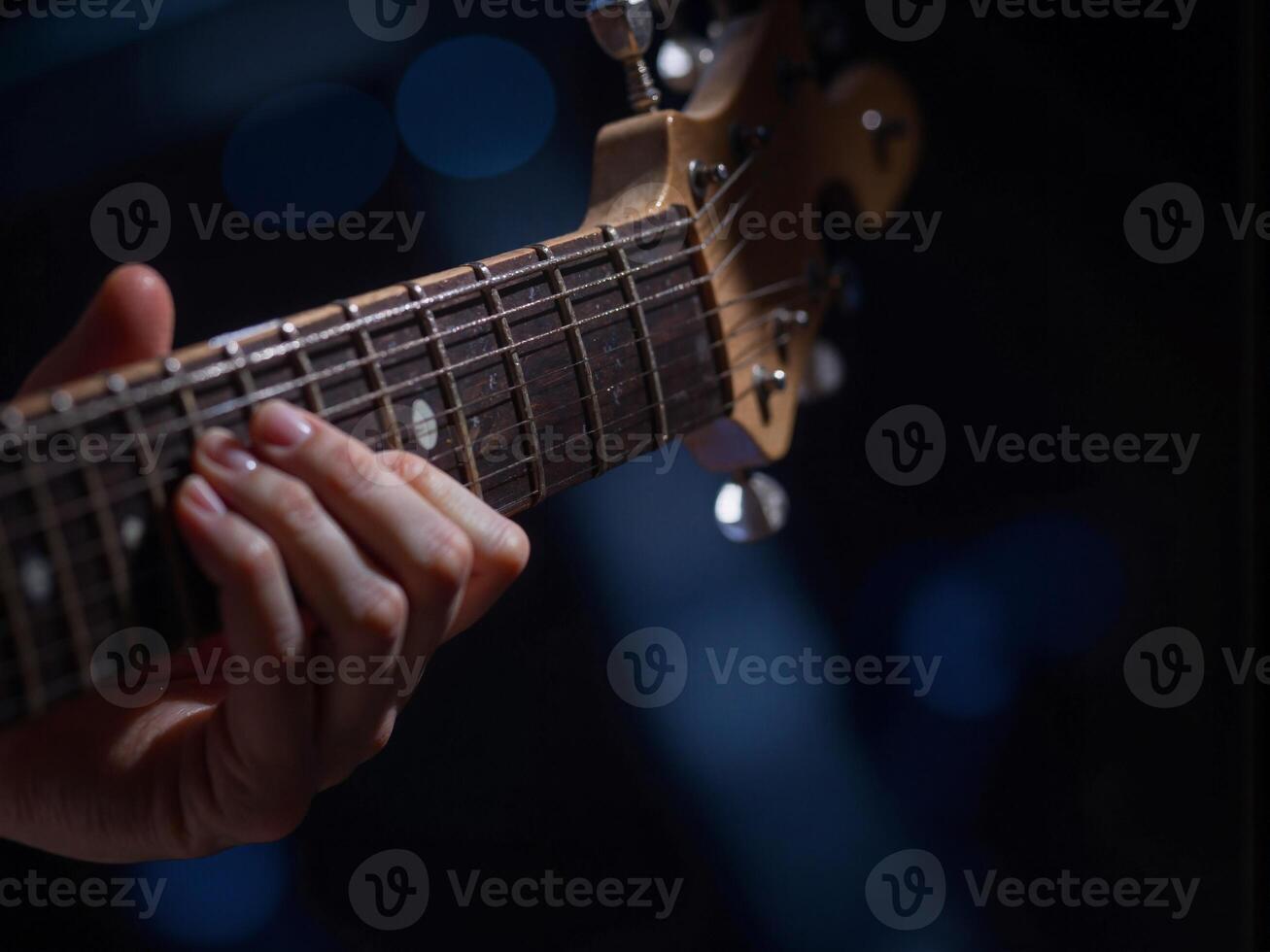 A person playing an electric guitar on a dark background photo