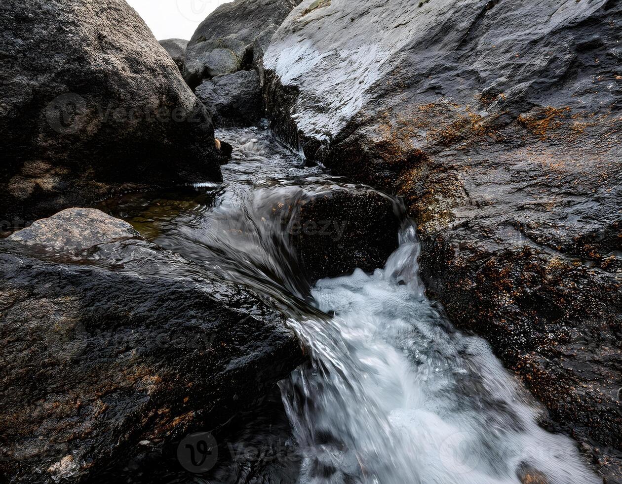 Transparent Water Cascading Over Dark Volcanic Rocks photo