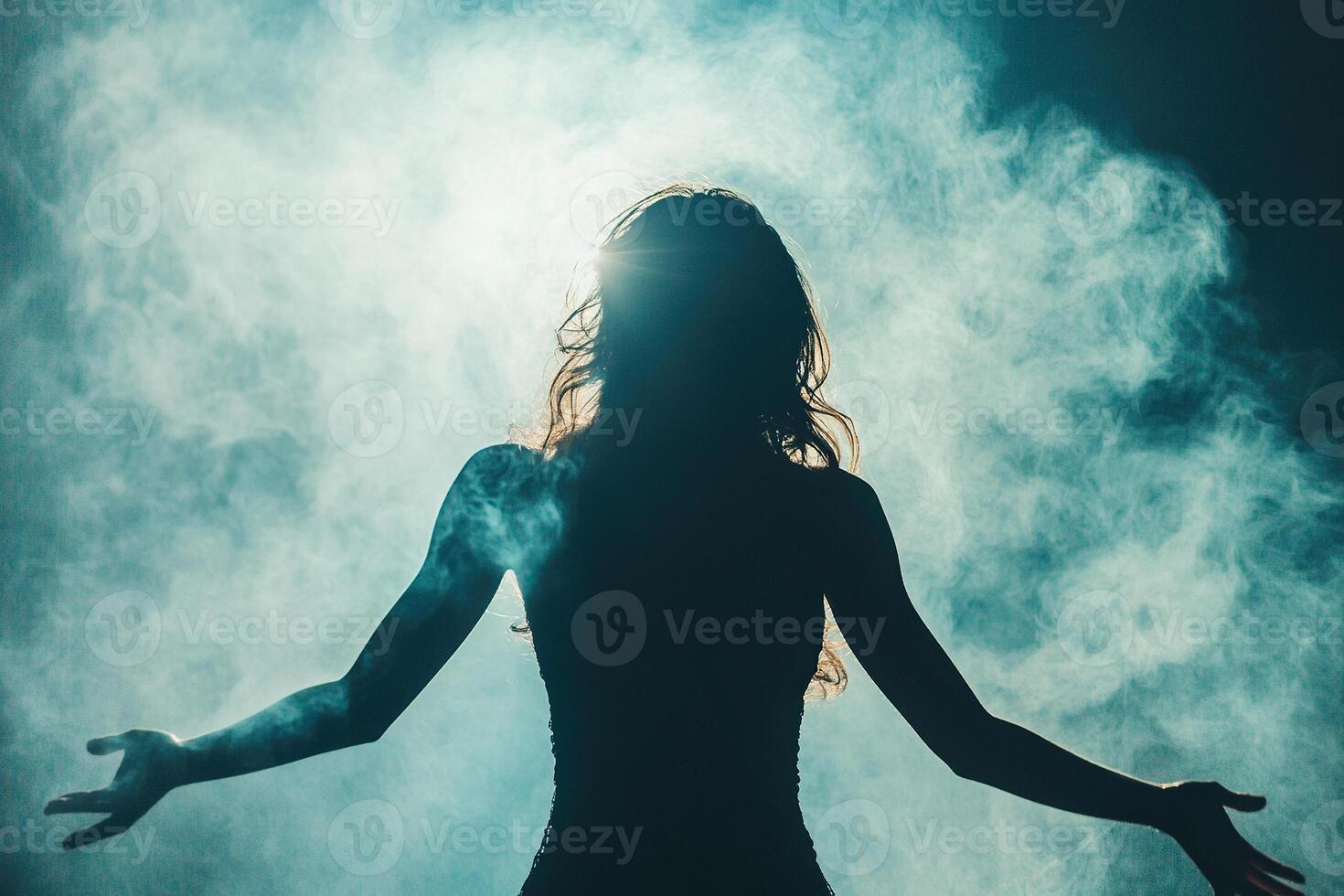 The silhouette of a woman in clouds of thick smoke, illuminated by a bright spotlight. photo