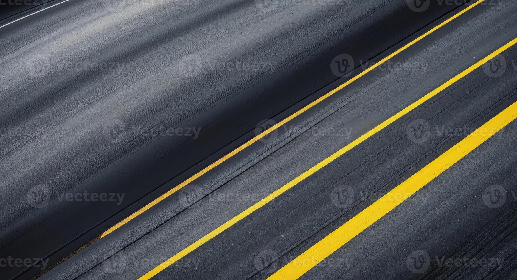 Curved asphalt road from a top view features smooth dark gray textures with yellow lines positioned diagonally for creative project backgrounds photo