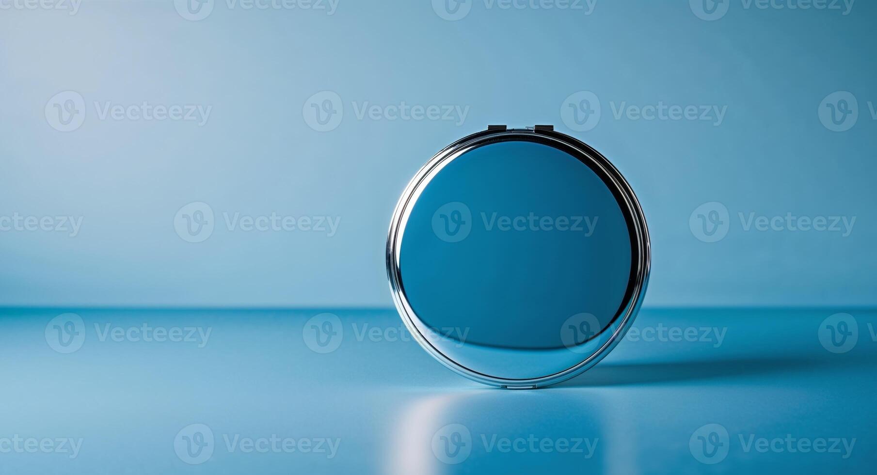 Reflective Surface of a Round Compact Mirror on a Blue Background. photo