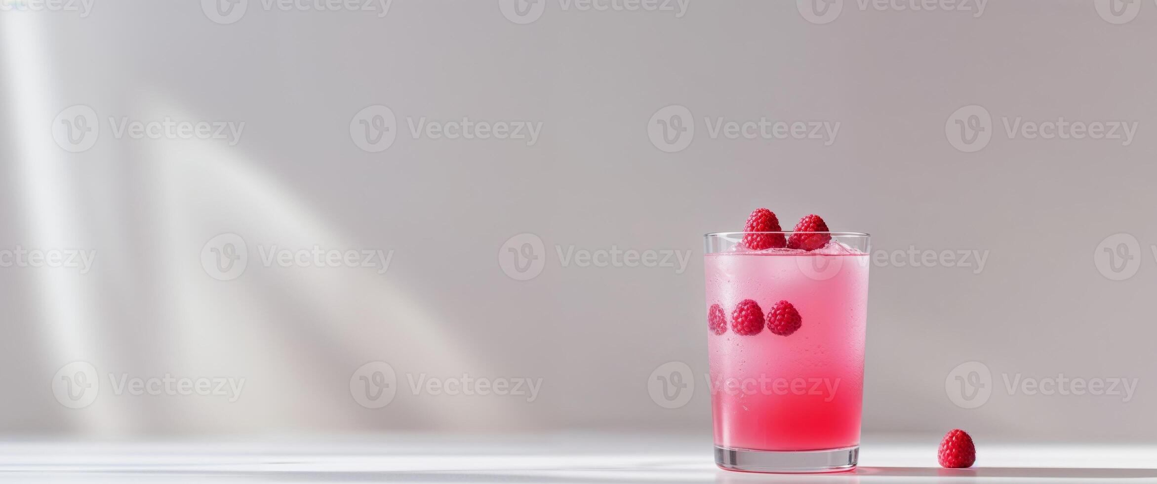 A glass of pink drink with raspberries on top photo