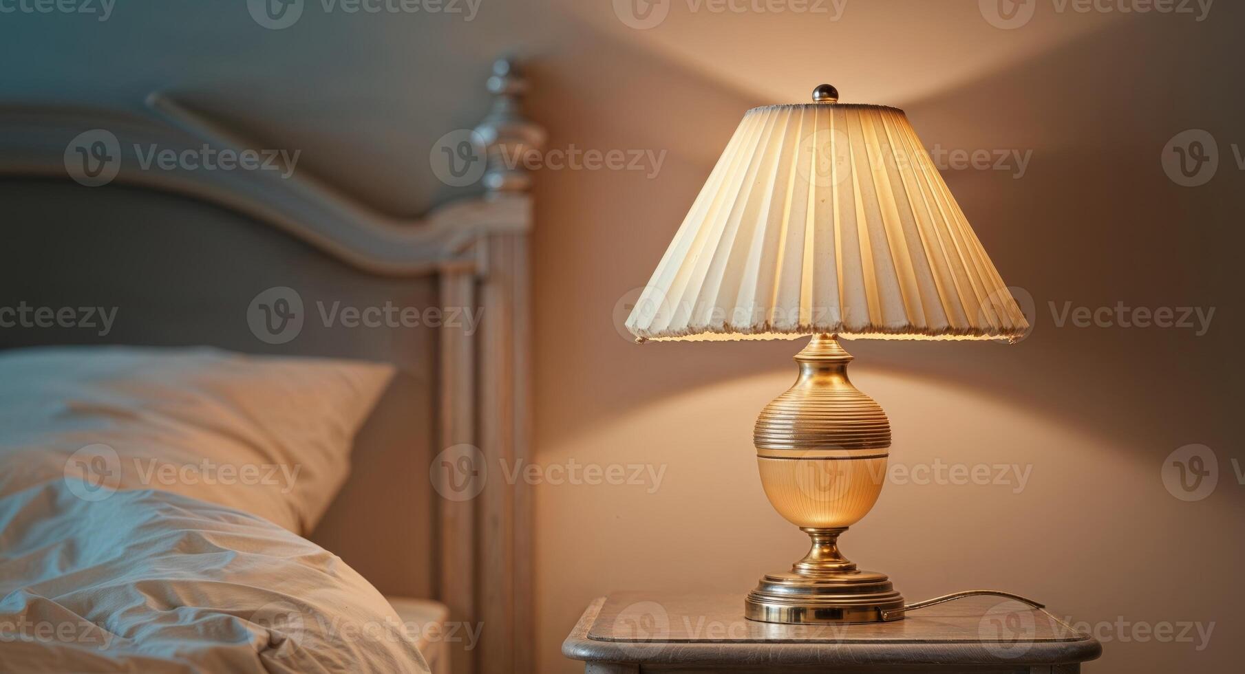 A lamp is on a nightstand next to a bed photo