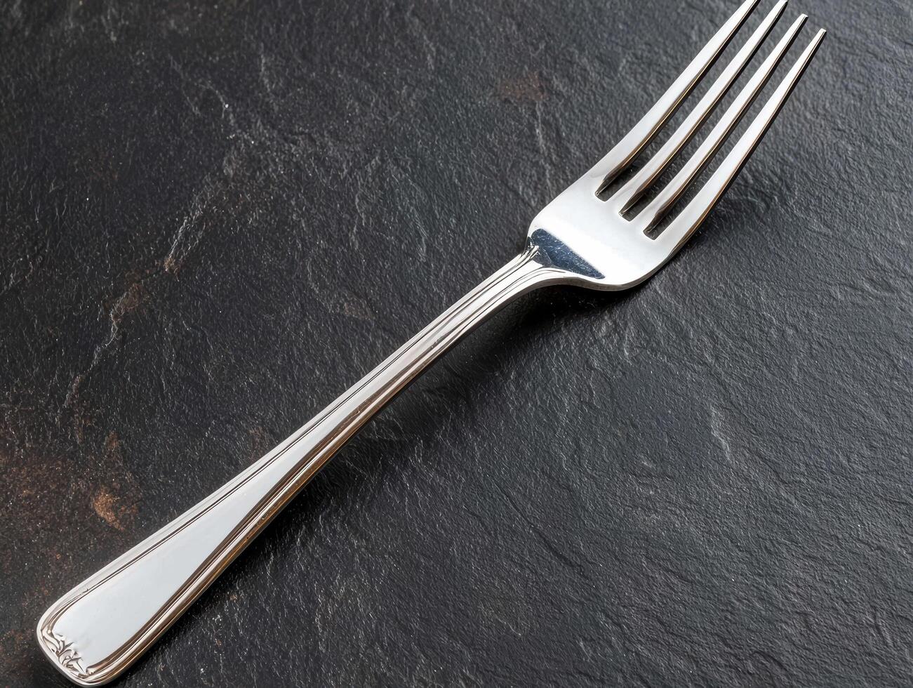 Elegant silver fork on a dark stone surface photo