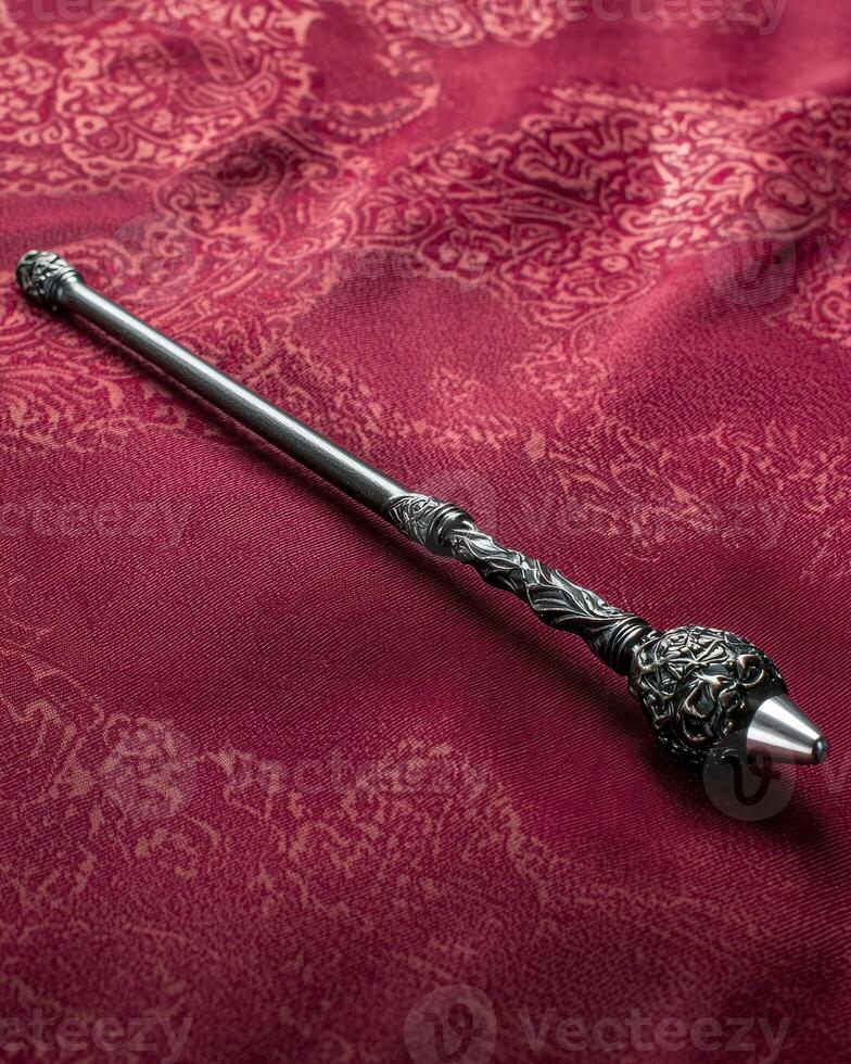 An ornate metal wand on a patterned red cloth photo