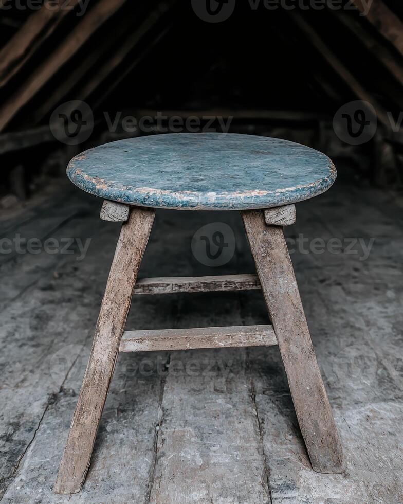 A rustic wooden stool sits in an old attic photo