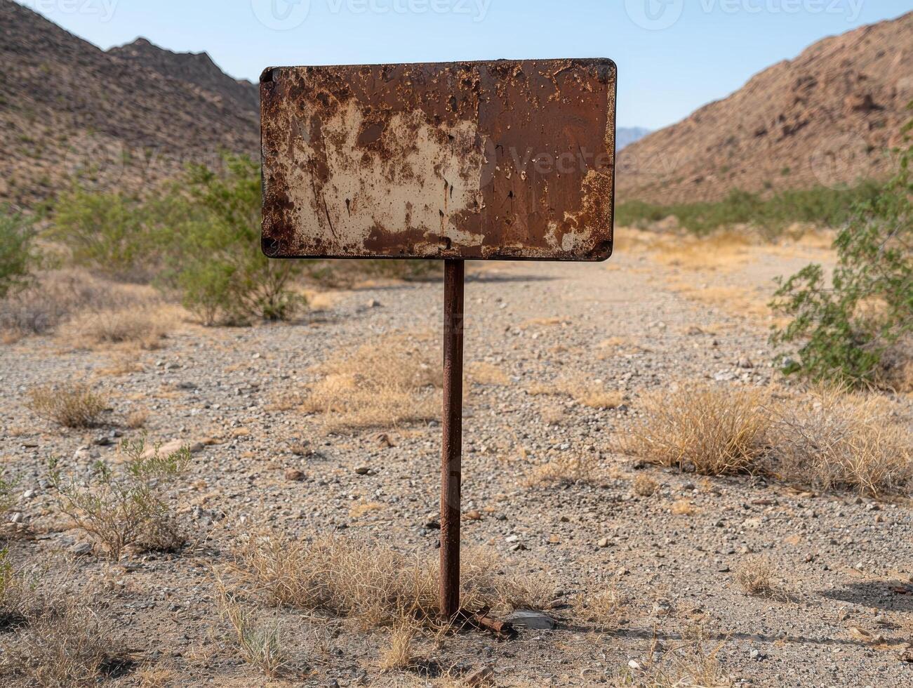 A weathered sign stands in the desert landscape photo
