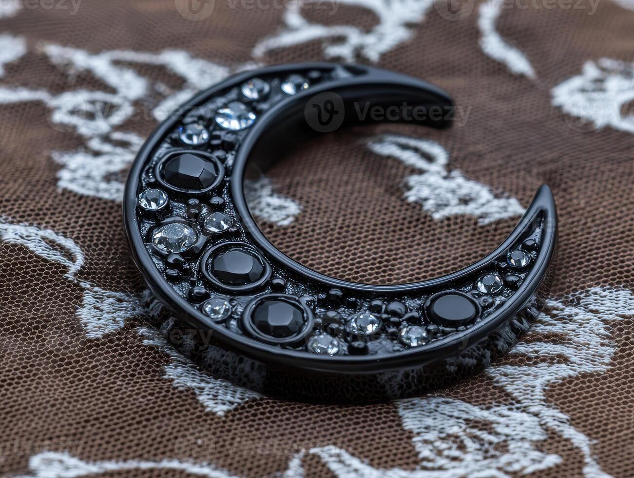 A black crescent moon shaped ornament with embedded gems photo