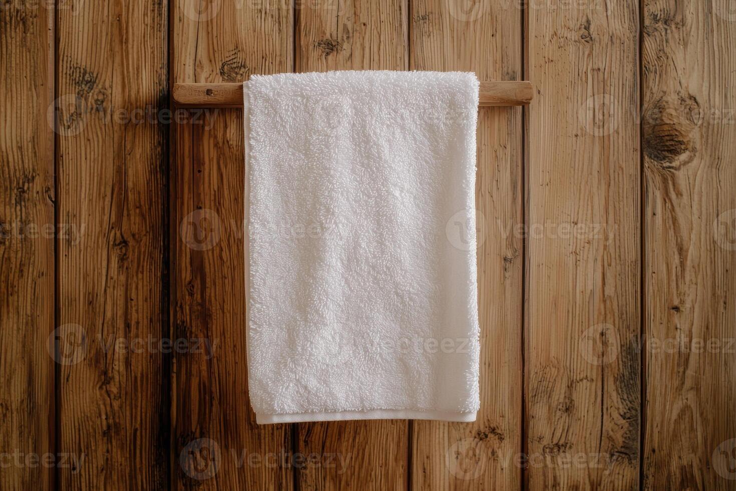 A white towel hangs on a wooden rack against a wood panelled wall photo