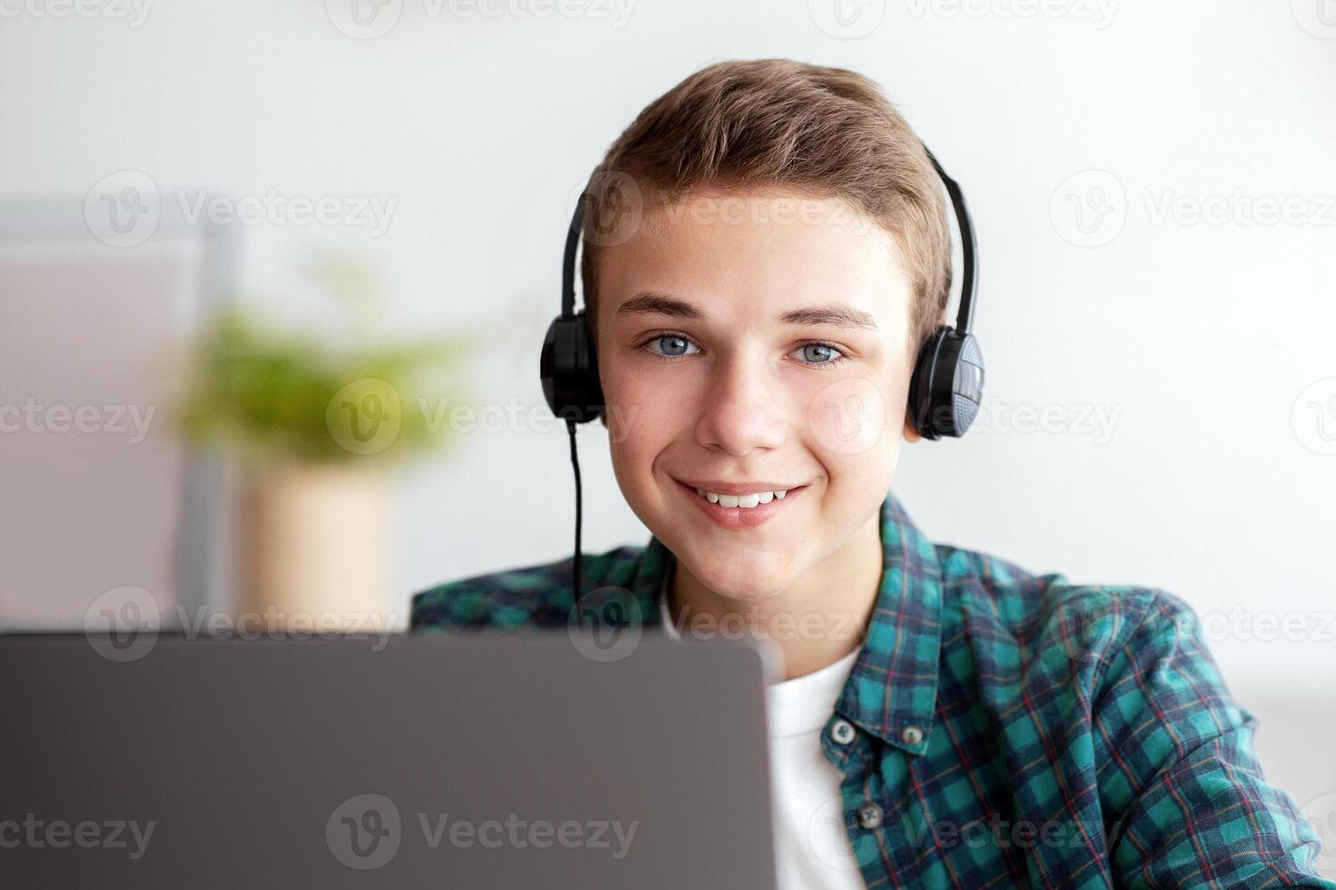 Happy guy in headset using laptop, spending time at home, empty space photo