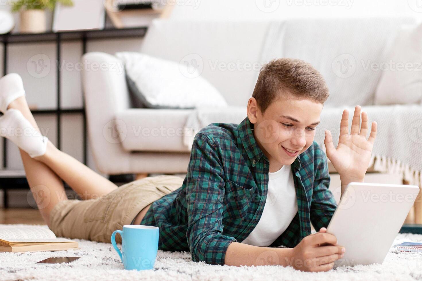 Schooler having videochat with friends on digital tablet from home, communication during isolation, free space photo