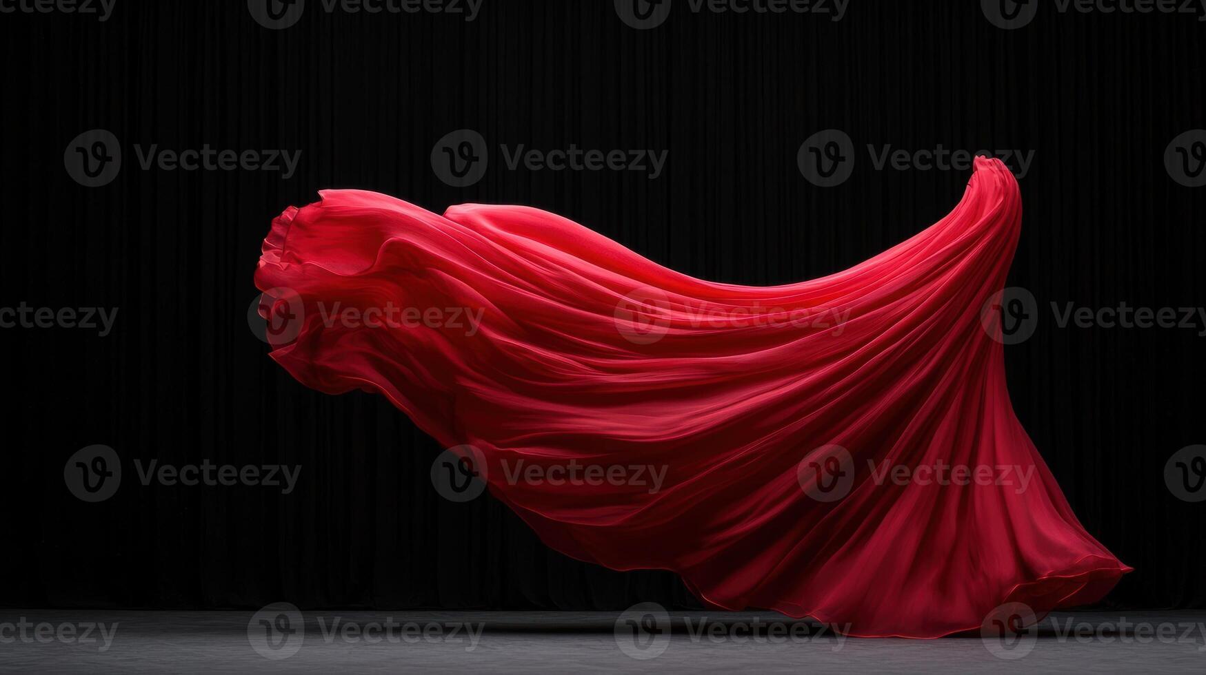 A flowing red silk fabric against a dark backdrop photo