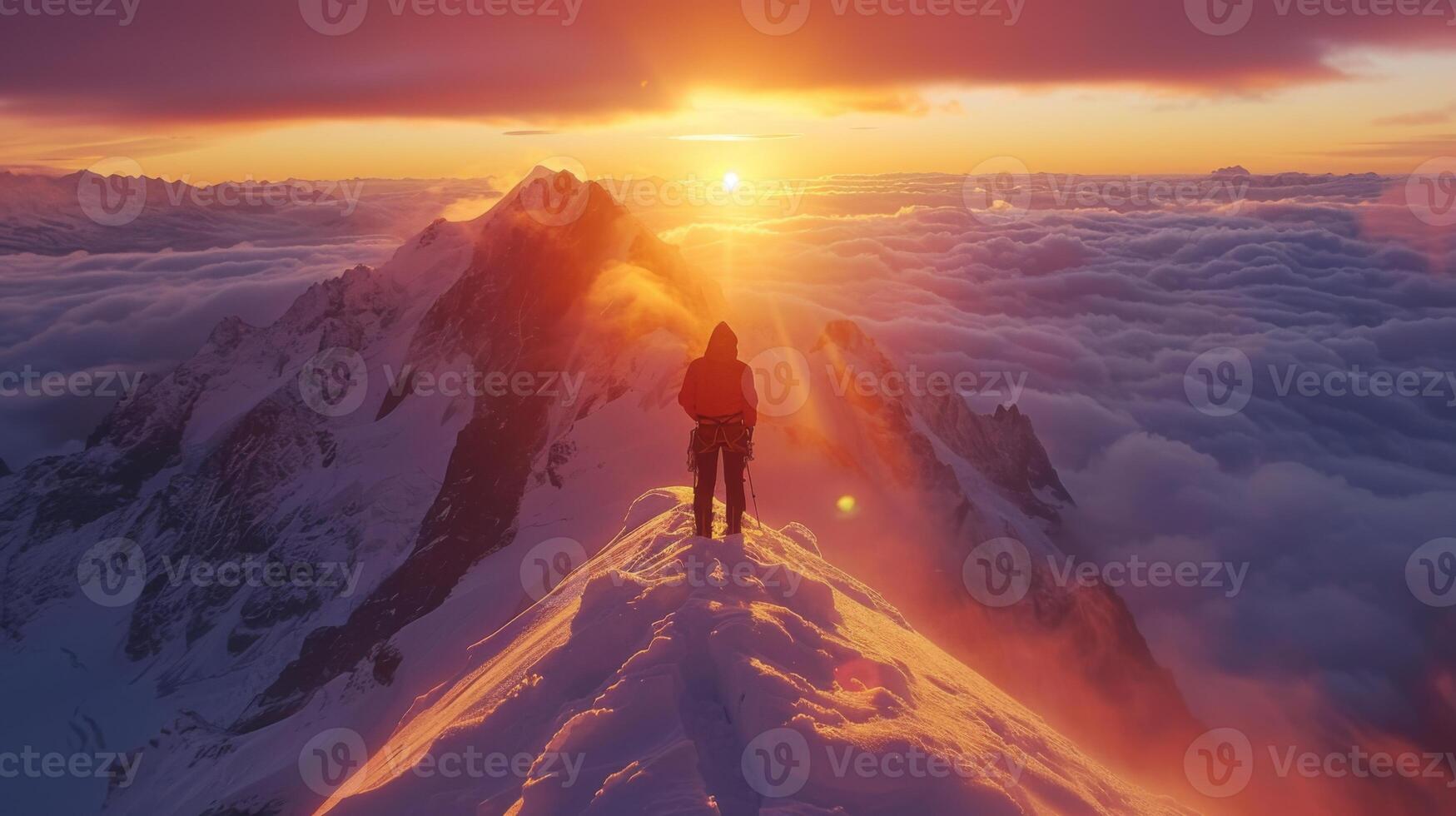 A climber stands on a snowy mountain peak as the sun sets, casting a warm glow over the clouds and surrounding peaks. The breathtaking landscape showcases nature's beauty and tranquility. photo