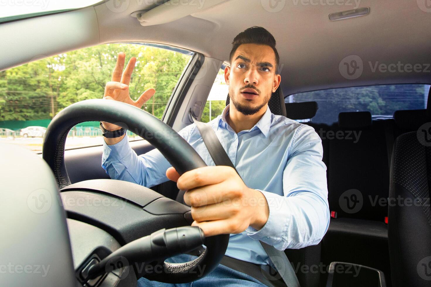 Irritated middle eastern businessman driving auto, fighting with other drivers on road, emotional arab man getting late for business meeting, stuck in traffic, yelling and gesturing, copy space photo