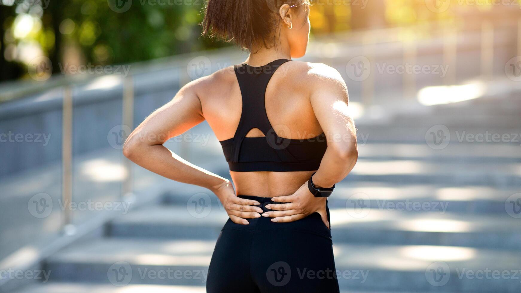 Closeup of black girl having lower back pain, got hurt during exercising at park, rear view, copy space photo