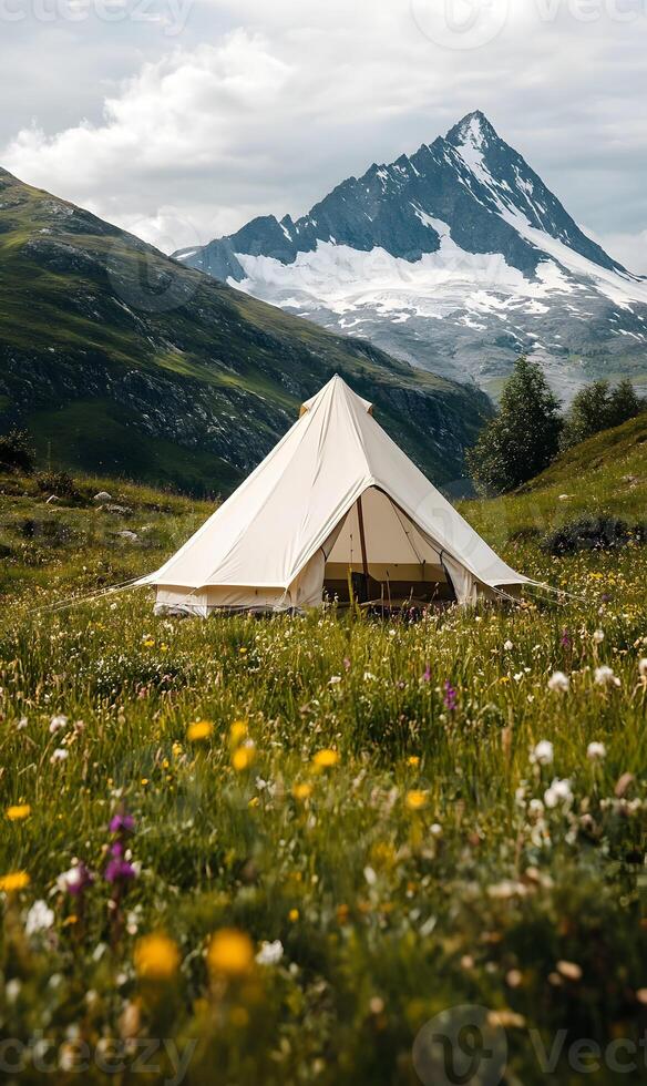 Idyllic camping scene with a canvas tent nestled amidst wildflowers and a mountain view photo