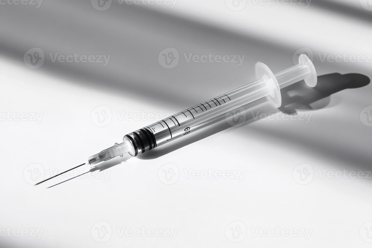 Medical syringe casting a shadow on white surface photo