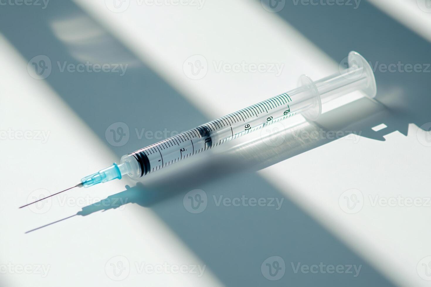 Medical syringe casting a shadow on a white surface. photo