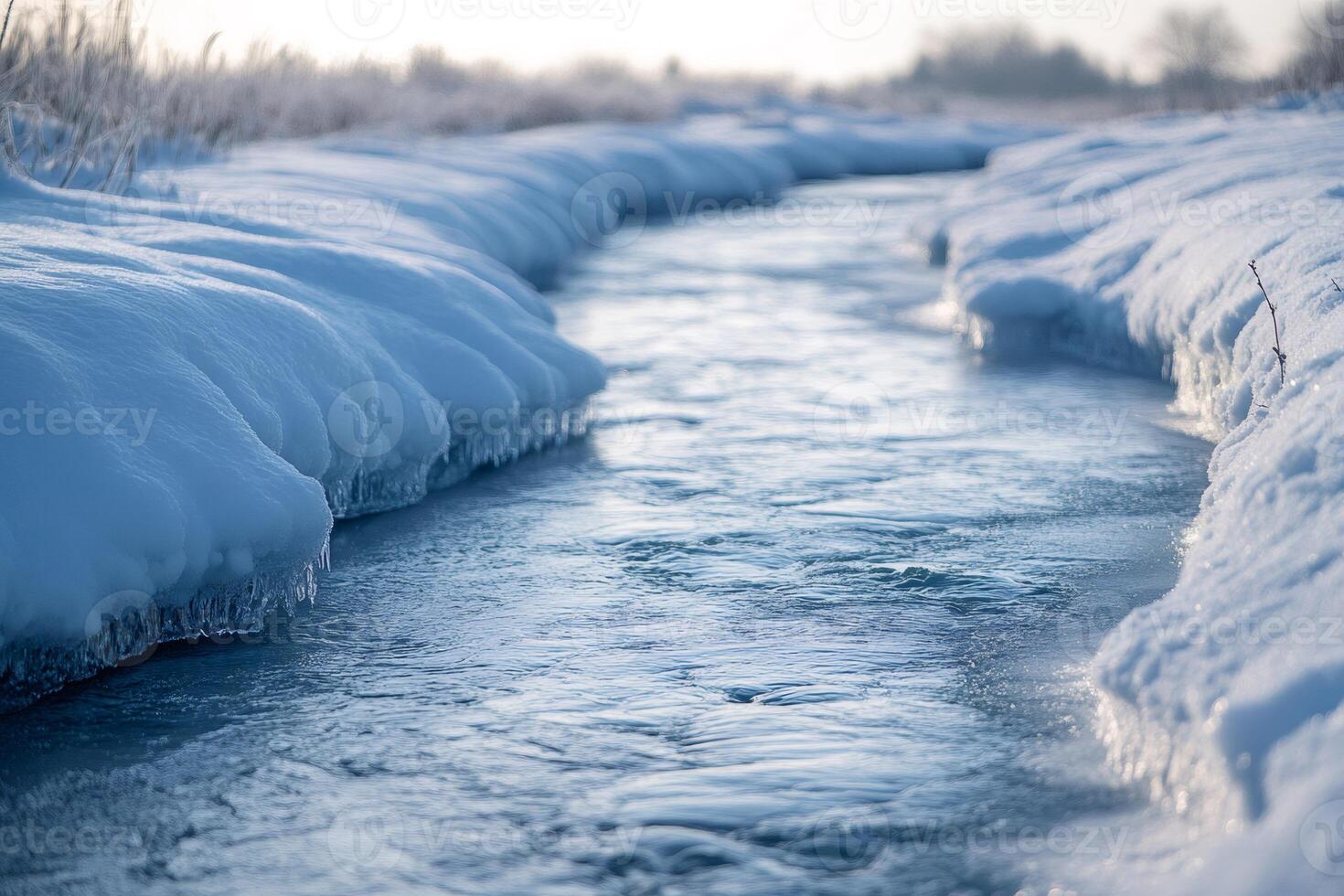 Small river flowing between snowy banks in winter photo