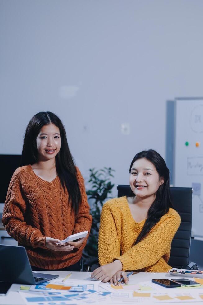 Two women sitting at a table with a laptop photo