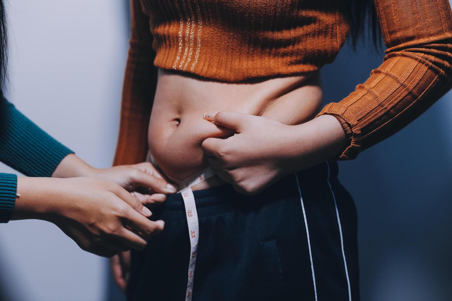 A woman is measuring her waist with another woman photo