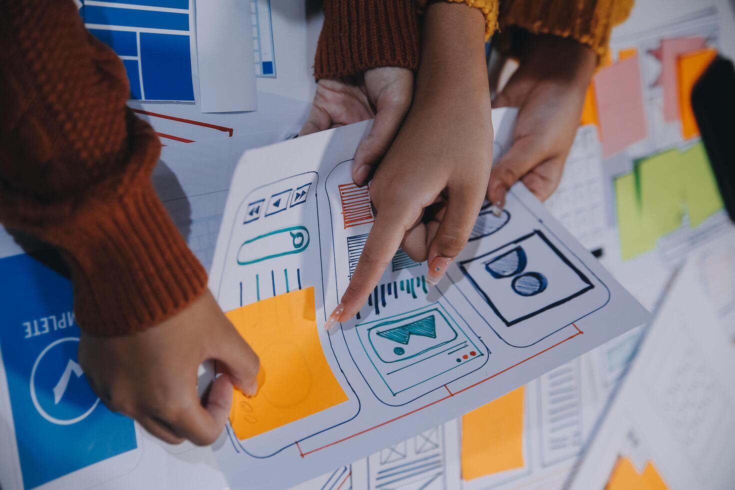 Two people holding up paper with various designs on it photo