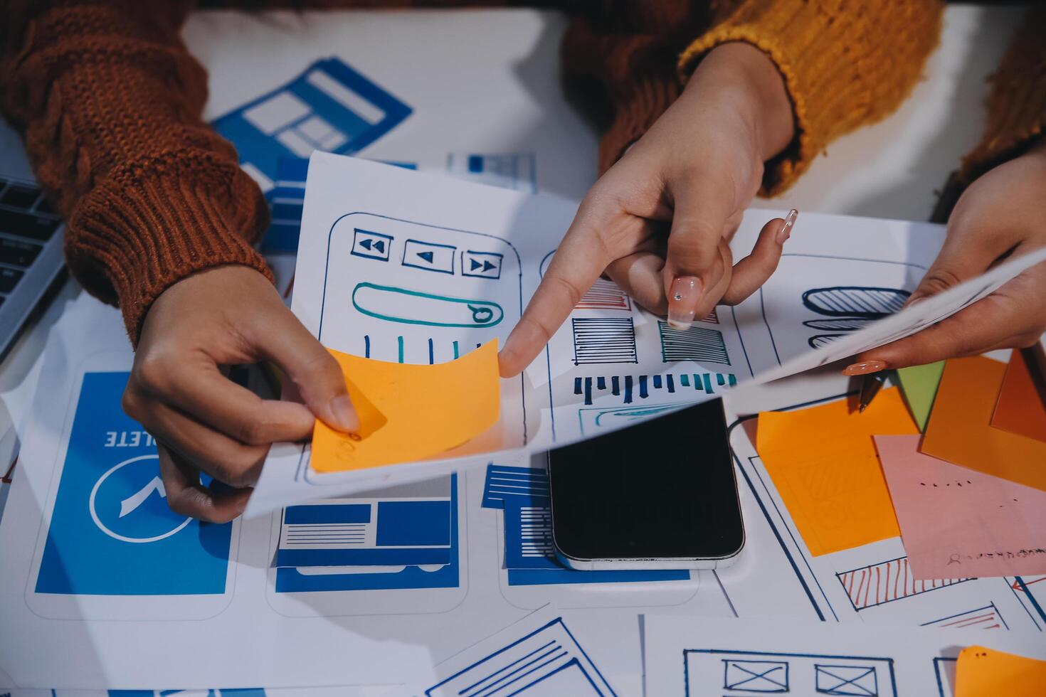 Two people working on a laptop with paper and sticky notes photo