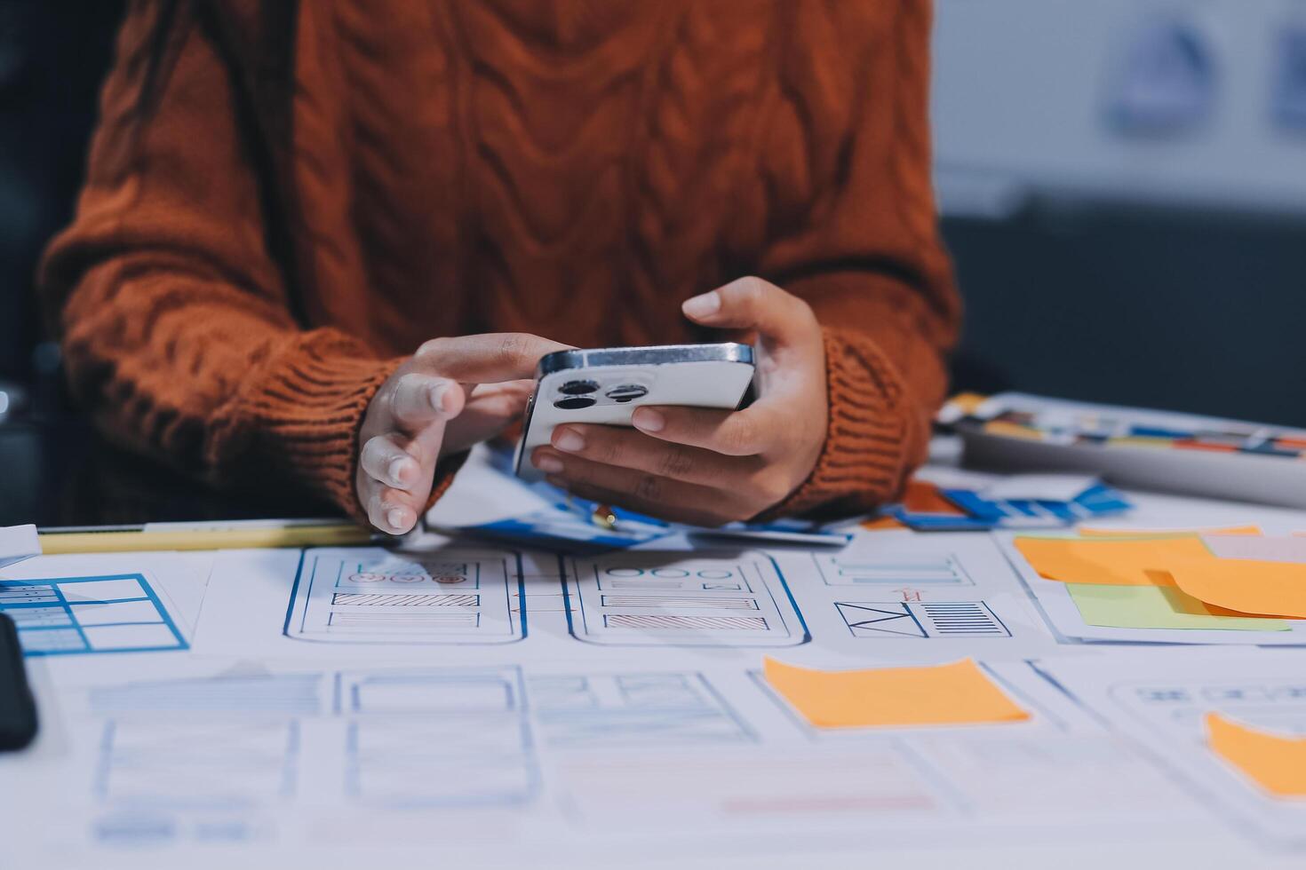 A person is using a cell phone while sitting at a desk photo