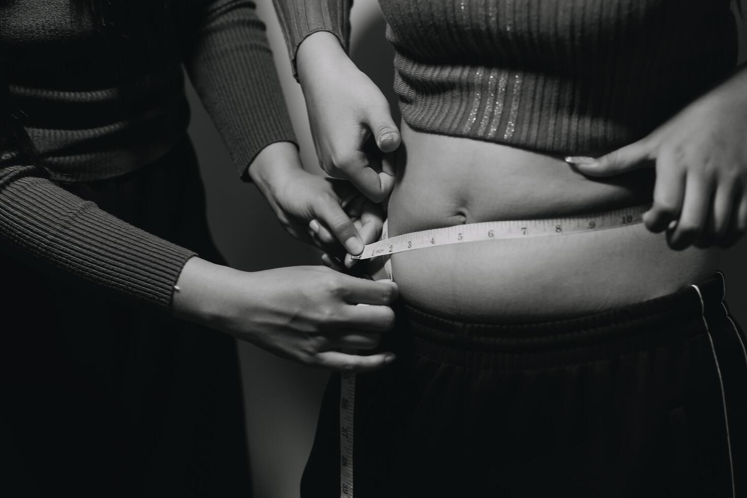 A woman measuring her waist with a tape measure photo
