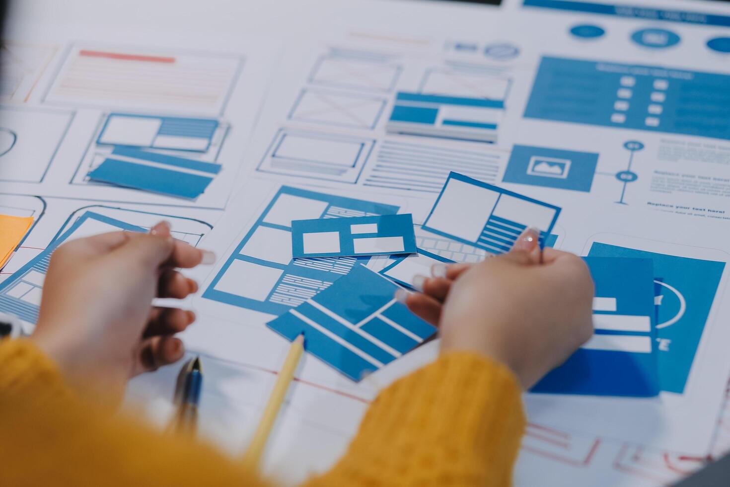 A person is working on a design project with blue and yellow paper photo