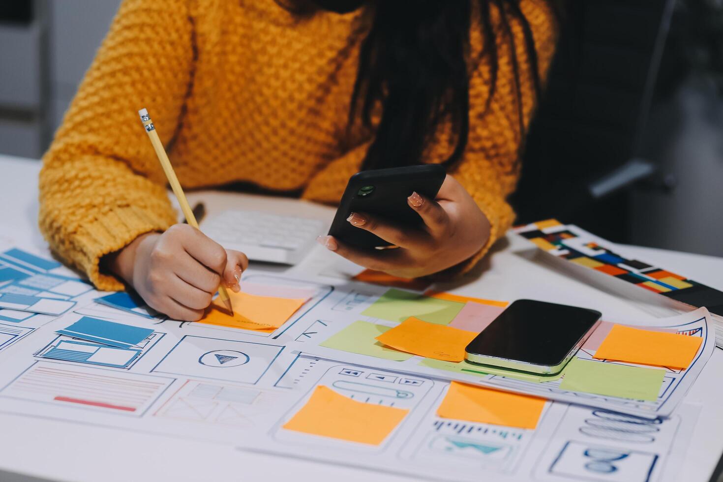 A woman is sitting at a desk with a phone and a notebook photo