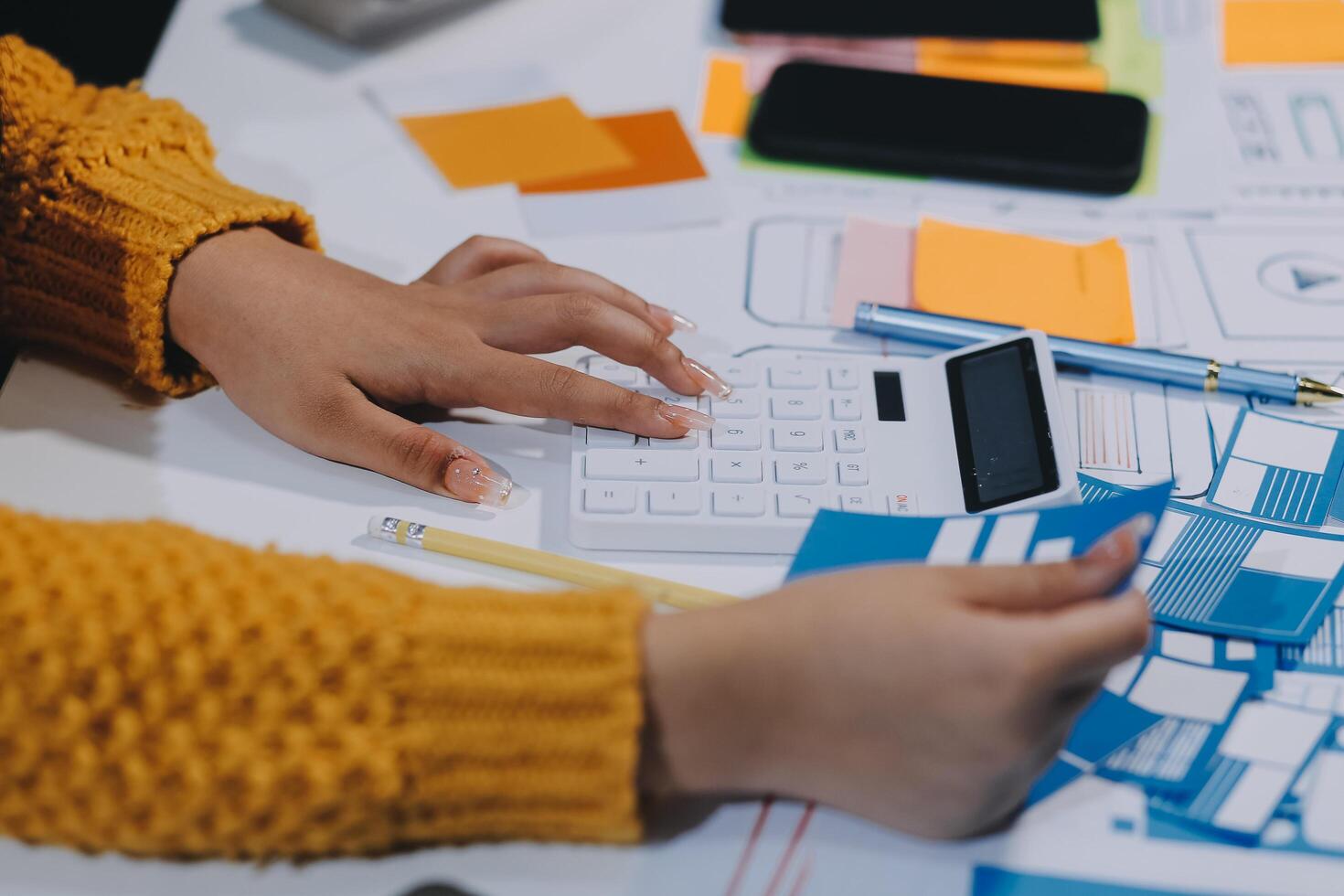 A person using a calculator on a desk with other papers photo